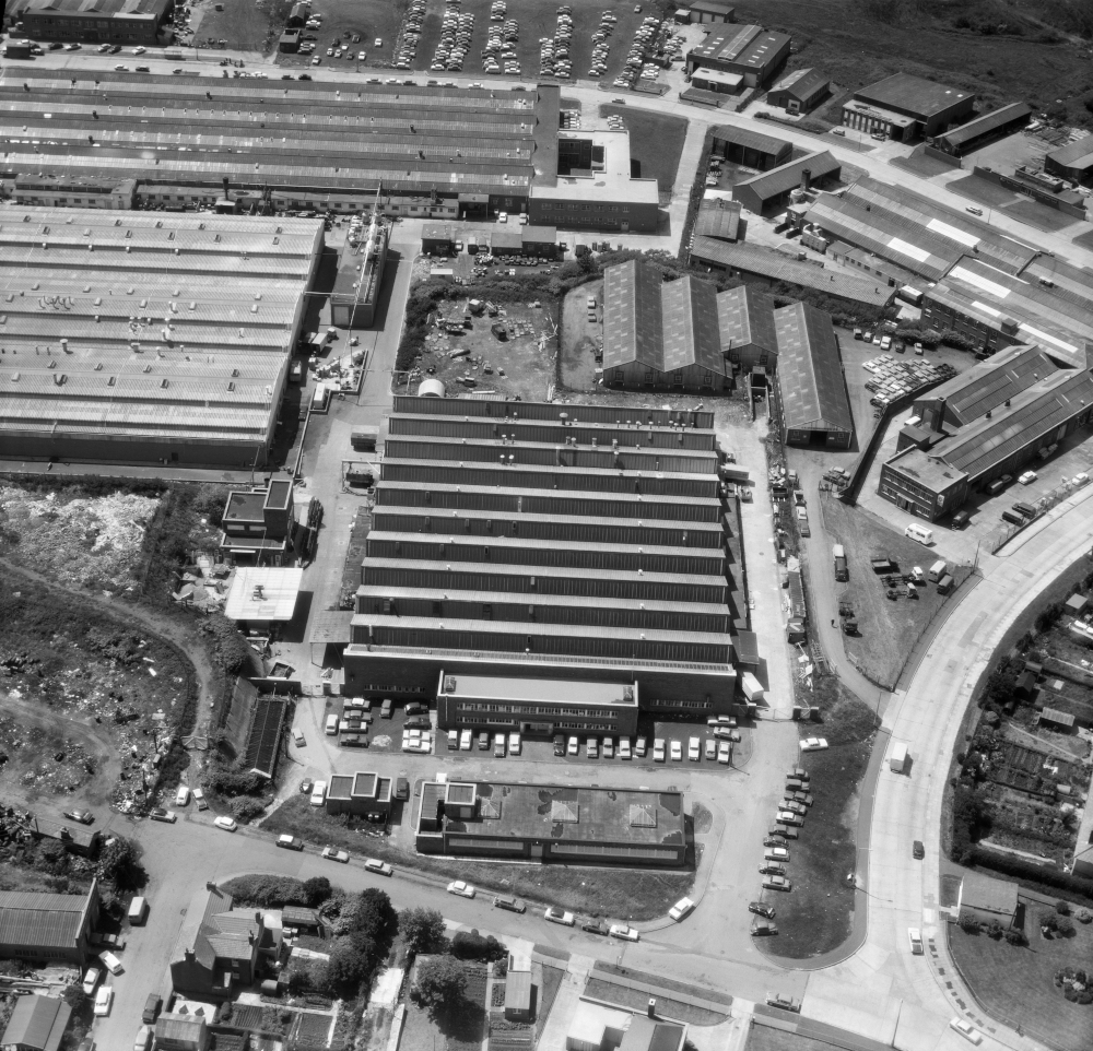 An aerial view of the factory showing large building with 11 gabled roofs and separate buildings around.